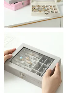Détail de la boîte à bijoux en velours gris avec couvercle en verre et compartiments.