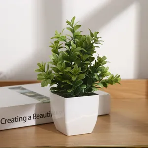 Vue détaillée de plante verte artificielle en pot carré en plastique, faux eucalyptus pour bureau.