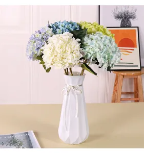 Vue détaillée du bouquet de fleurs d'hortensia artificiel coloré dans un vase blanc déco.