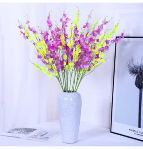 Artificial dancing orchid flower arrangement detail, ceramic vase home decor scene view.