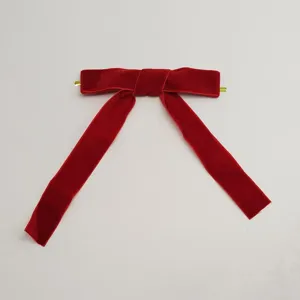 Detailed close-up of a red velvet Christmas bow with a gold wire tie for holiday decor.