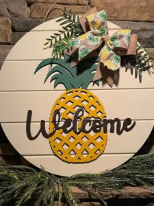 Ananas Holz Willkommensschild Detail, rustikale Hängeplakette mit grünen Blättern und Schleife.