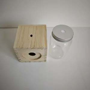 Wooden carpenter bee trap detail view showing the drilled wood block and clear container.