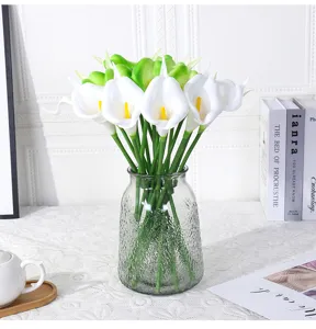 Detail van kunststof PU calla lelie boeket, mini nepbloemen in glazen vaas voor huisdecor.