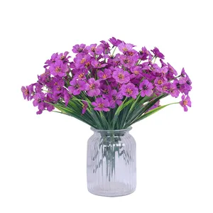 Purple artificial silk flowers bouquet in transparent glass vase for home wedding decor.