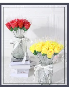 Detailansicht eines künstlichen Rosenblumenstraußes in einer Glasvase mit Geschenkverpackung.
