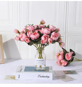 Detailansicht künstlicher rosafarbener Pfingstrosen Seidenblumen in Glasvase mit Buchdekor.