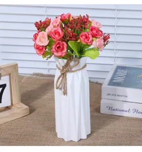 Detail view of a modern minimalist plastic flower vase with artificial roses for home decor.