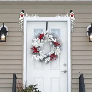 Detailed view of Christmas snowman door corner decor and festive white and red wreath on door.