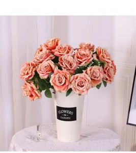 Detailaufnahme eines rosa künstlichen Rosenstraußes in einem weißen Vintage-Blumenkübel.