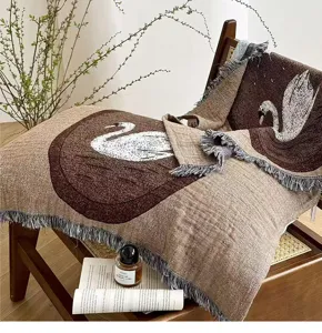 Detail view of brown woven pillow towel with swan pattern and stylish tassels in home decor setting.