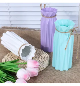 Close-up detail of modern plastic flower vases with rustic hemp rope tied around the pleated neck.