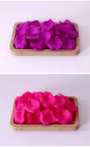 Nahaufnahme von künstlichen Rosenblüten in Lila und Pink auf Holztabletts arrangiert.