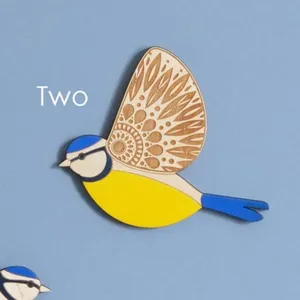 Wooden flying bird wall decor detail showing laser engraved wing and blue yellow design