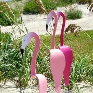 Pink metal flamingo lawn ornaments in outdoor garden sand setup