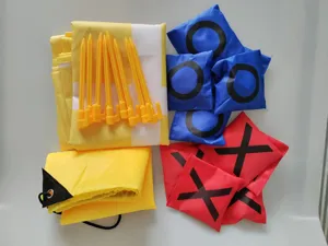 Bean bag throwing game detail, yellow grid mat with stakes and red blue X O bean bags.