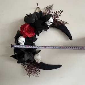 Gothic Halloween crescent moon wreath with skulls red rose and black leaves for home decor.