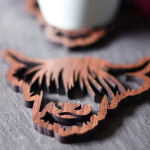 Detailed closeup of a wooden highland cow coaster, showcasing natural wood grain and hollow design.