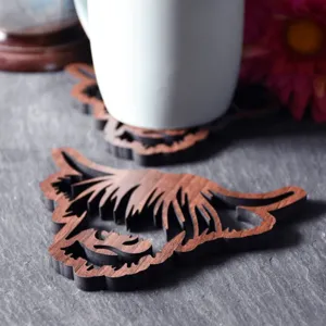 Close-up view of wooden highland cow coaster on slate surface with detailed cutout.