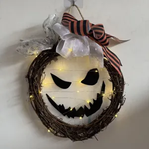 Ghirlanda di rami luminosa di Halloween con viso spaventoso e fiocchi per decorazione.