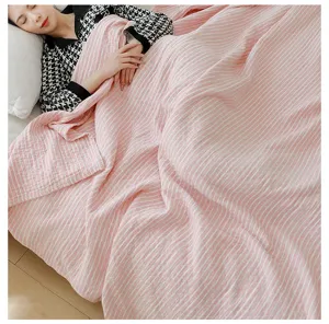 Detail van roze witte gestreepte gazen deken, zachte ademende zomerdeken voor op bed.