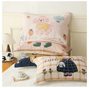 Cotton gauze pillow towel detail shot, showing cute cartoon print and stacked design on bed.