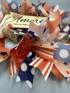 Close-up detail of patriotic ribbon wreath with stars and stripes pattern for door decor.
