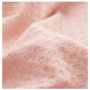 Close-up detail of soft pink waffle weave fabric, breathable and comfortable texture.
