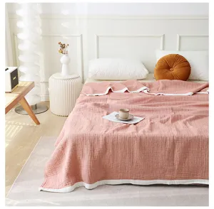 Vue détaillée de la couverture en gaze de coton rose dans une chambre, douce et respirante.