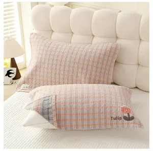 Vue détaillée d'une housse de coussin en gaze de coton douce avec motif carreaux et broderie.