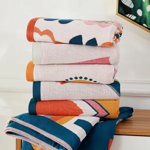 Coperte in garza di cotone con motivi geometrici impilate ordinatamente per uso domestico quotidiano.