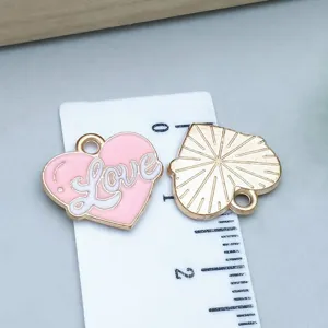Macro detail of pink enamel heart charm with Love script and golden sunburst back