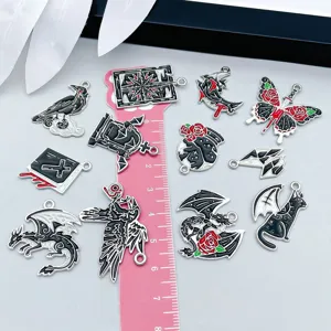 Detailed close-up of twelve gothic enamel charms with a ruler for scale reference