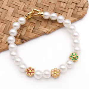 Primer plano de una elegante pulsera de perlas con dijes de margaritas esmaltadas