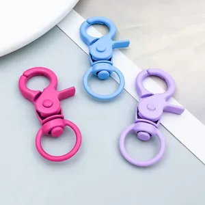 Dettaglio di tre moschettoni girevoli in lega colorata nei toni rosa, blu e viola.