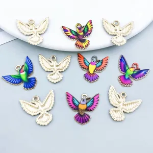 Close-up of colorful enamel hummingbird and gold bird alloy pendants for DIY jewelry