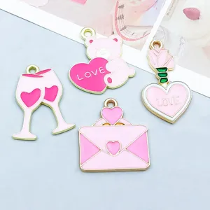 Macro detail of pink enamel Valentine's Day heart, teddy bear, and wine glass charms