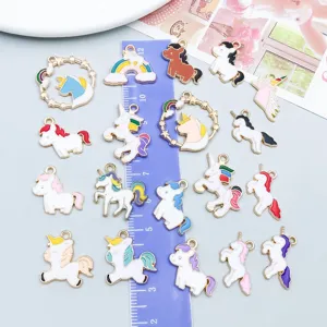 Detail view of 20 colorful enamel unicorn charms with a ruler for size reference.