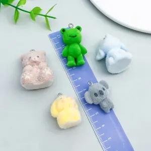 Detailed macro view of flocked cartoon animal charms with a ruler showing scale for DIY jewelry