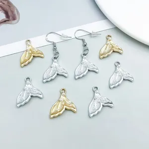 Detailed macro shot of gold and silver mermaid tail charms with white pearls.