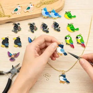 Gros plan de création de bijoux DIY avec des breloques d'oiseaux en émail coloré