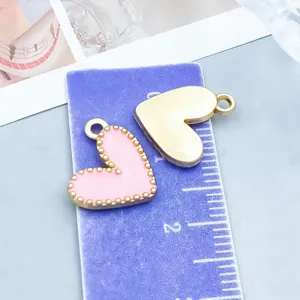 Vue détaillée de breloques en forme de cœur en émail rose et or avec règle violette
