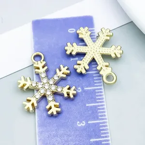 Macro view of gold and rhinestone snowflake charms for jewelry making with size scale