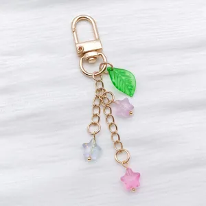 Close-up of translucent glittery star beads and green leaf charm on a gold keychain