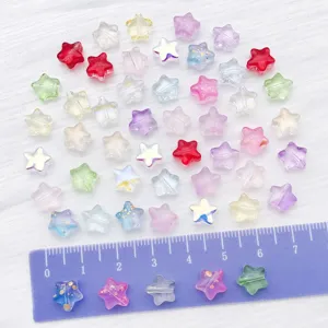 Close-up of colorful translucent star beads with gold foil details and a ruler for scale.