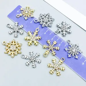 Detailed view of rhinestone snowflake charms in gold and silver tones with a ruler.