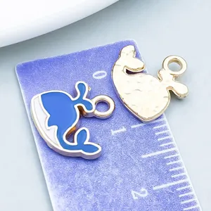 Close-up detail of a blue and white whale enamel charm next to a purple measuring ruler.