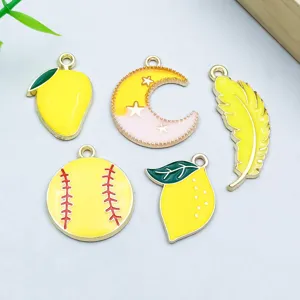 Close-up of five yellow enamel charms: mango, moon, feather, baseball, and lemon.