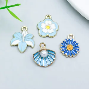 Close-up of four lake blue enamel alloy charms with delicate floral and seashell designs