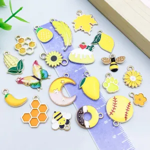 Collection of mixed yellow enamel alloy charms shown with a ruler for size reference